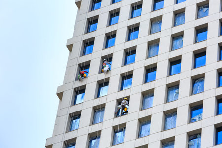 Hochiminh City, Vietnam - September 19, 2015: Dangerous job of the workers cleaning the glass...