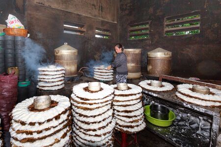 Binh Thuan province, Vietnam - October 12, 2015 at a small factory, where produces rice noodle, the woman Brings basket full of noodles print to the steamer. This is a hard work to make a very tasty traditional Vietnamese dishのeditorial素材