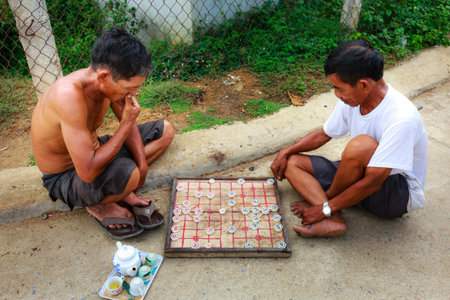Binh Thuan province, Vietnam - October 12, 2015: Two men are playing chinese print rural area on the...