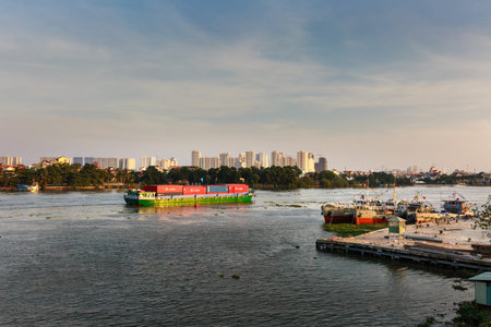HoChiMinh city, Vietnam - February 7, 2016: Maritime transport on the river, loading container vessel on SaiGon river, residential and apartment at riverside, scene of industrial city, Vietnamのeditorial素材