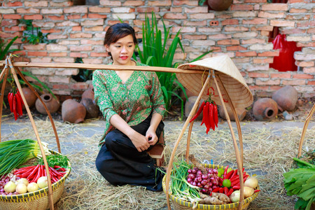 Hochiminh City, Vietnam - March 5, 2016 : salesgirl with her bamboo basket full of vegetables in the culinary fair at the Van Thanh tourist area, Ho Chi Minh City which is modeled on the traditional market in the village Vietnamのeditorial素材