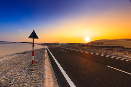 Road through desert landscape under sunset sky. Dramatic sunset sky in the desert.の写真素材