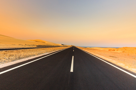 Road through desert landscape under sunset sky. Dramatic sunset sky in the desert.の写真素材