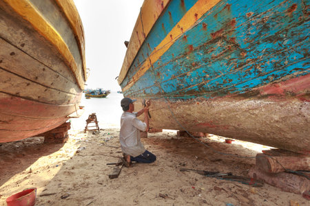 Lagi beach, Binh Thuan province, Vietnam - March 28, 2016 : at a repair workshop fishing boats. Skilled workers are repairing fishing boats for fishermenのeditorial素材