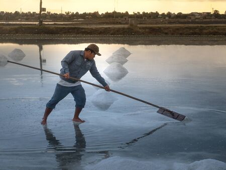 Ninh Thuan Province, Vietnam - February 28, 2016 :the worker are working on salt field at dawn. Salt field Hon Khoi in Nha Trang, Viet Nam. Workers transporting salt from the fields Hon Khoi, Viet Nam.のeditorial素材