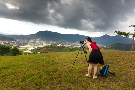 Da Lat City, Lam Dong Province, Vietnam - July 02, 2016 :Sloping meadows with Lonely tree on the hill at beautiful landscape on cloudy day in summer. woman  who is hunting the beautiful moment to take photos in twilightのeditorial素材