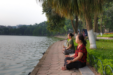 Ha Noi, Vietnam - September 21, 2016 : the women is sitting meditation beside Hoan Kiem lake on a sunny morning. Hoan Kiem Lake is the center of the capital, Hanoi, morning people are excited when exercising or walking around the lakeのeditorial素材