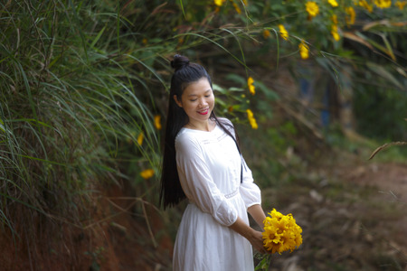Bao Loc, Lam Dong Province, Vietnam - November 5, 2016 : young girl holding a bouquet of freshly picked wild sunflower between the bushes of wild sunflower bloom in yellow, colorful sceneのeditorial素材