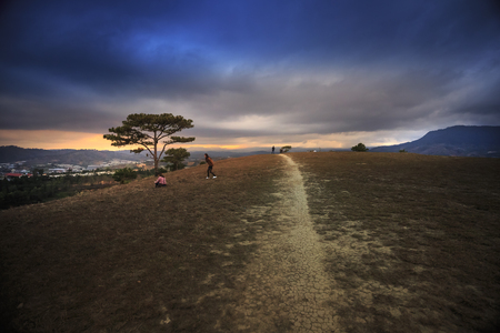 Da Lat town, Vietnam - February 19, 2017: trail on the hill at sunset with beautiful young girls playing on hillのeditorial素材