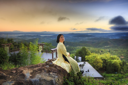 "Linh Qui Phap An" temple, Bao Loc, Lam Dong Province, Vietnam - February 28, 2017 : woman wearing traditional dress aodai sitting relaxed on the yard of "Linh Qui Phap An" temple near Bao Loc townのeditorial素材
