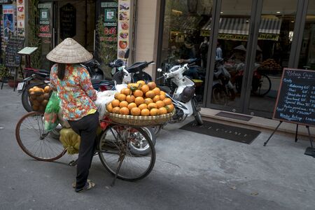 Old Town in Hanoi, Vietnam - March 4, 2018: A rural woman sells fruit in an ancient street in Hanoi, Vietnam.のeditorial素材