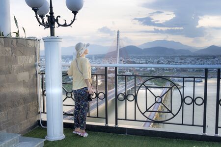 Da Nang city, Vietnam - June 30, 2018:  a female tourist sightseeing Da Nang City and cable-stayed Tran Thi Ly in the sunset. The bridge crosses the Han River, view from above at Da Nang city, Vietnamのeditorial素材