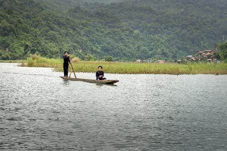 Ba Be lake, Bac Kan province, Vietnam - July 14, 2018: Ethnic Tay women in traditional costume are the rowing dugout (the boat made from a single tree trunk ) on Ba Be Lake. Ba Be Lake is a famous tourist destination of Bac Kan Province, Vietnamのeditorial素材