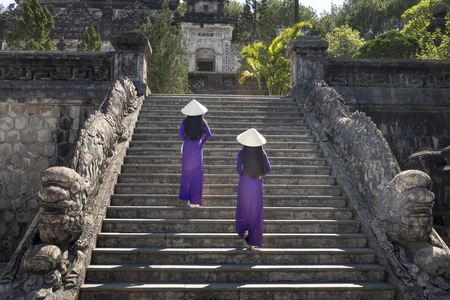 Two Vietnamese girls are gentle in culture traditional purple long dress at the Tomb of Khai Dinh King at Hue city, Vietnamの写真素材