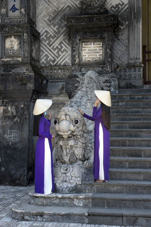 Two Vietnamese girls are gentle in culture traditional purple long dress at the Tomb of Khai Dinh King at Hue city, Vietnamの写真素材