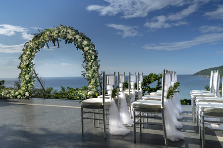 View of decorated wedding chairs with fabric and flowers near the beachの写真素材