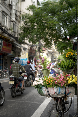 Hanoi capital, Vietnam - July 16, 2018: The street vendor sells flowers on the bicycle in the morning in Hanoi Old Quarter, Vietnam.のeditorial素材