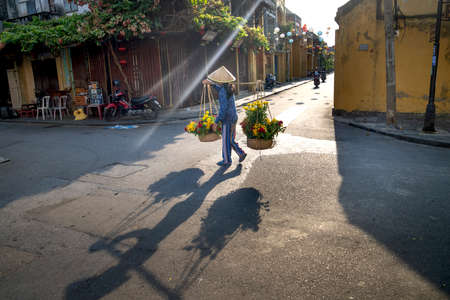 Hoi An Ancient Town, Quang Nam Province, Vietnam - May 10, 2020: Photo of a woman selling flowers on a pair of bamboo frames in Hoi An Ancient Town, Quang Nam Province, Vietnamのeditorial素材