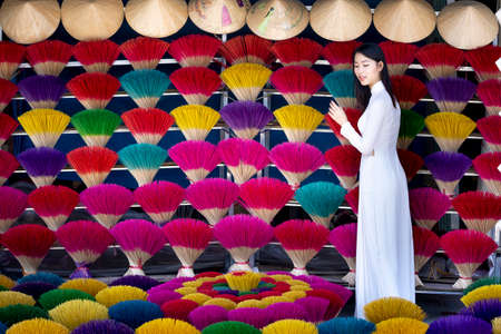 Hue City, Thua Thien Hue Province, Vietnam - May 8, 2020: An image of a Hue girl in a traditional ao dai costume with colorful bundles of incenseのeditorial素材