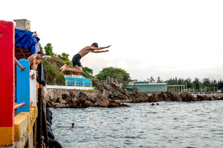 Vinh city, Nghe An province, Vietnam - July 31, 2020: Children jump to the beach to swim in a...