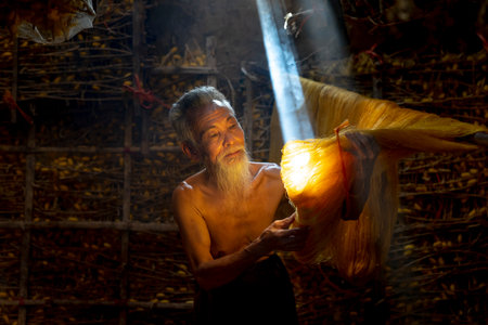 Vu Thu gold silk craft village, Thai Binh Province, VN - September 15, 2020: An old man is checking the quality of gold silk products in warehouse at Vu Thu gold silk craft village in Thai Binh, VNのeditorial素材