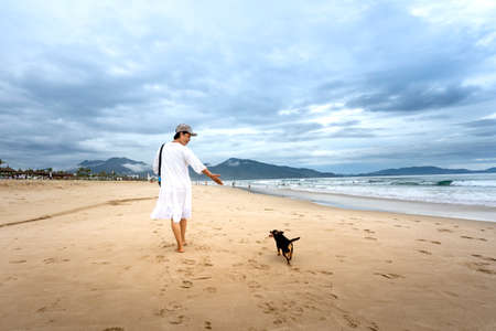 Bai Dai Beach in Cam Ranh district, Khanh Hoa province, Vietnam - October 7, 2020: a woman walking with her dog walk on the beach at a tropical resort in Cam Ranh district, Khanh Hoa province, Vietnamのeditorial素材