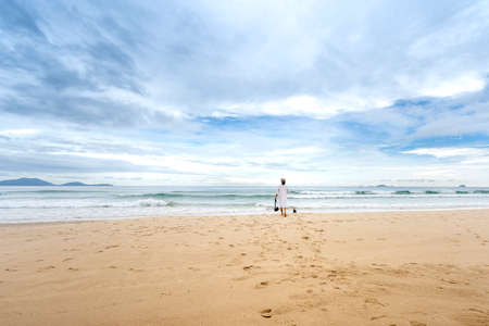 Bai Dai Beach in Cam Ranh district, Khanh Hoa province, Vietnam - October 7, 2020: a woman walking with her dog walk on the beach at a tropical resort in Cam Ranh district, Khanh Hoa province, Vietnamのeditorial素材