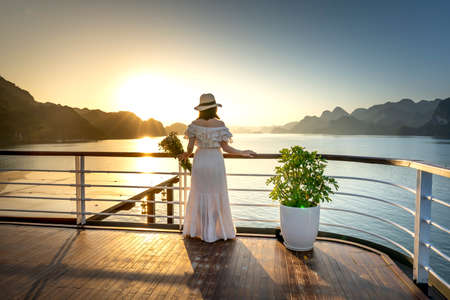 5-star Heritage Cruise on Lan Ha Bay, Quang Ninh province, Vietnam - November 13, 2020:Female tourist welcomes the sunrise on the deck of the 5-star Heritage Cruise on Lan Ha Bay, Quang Ninh, VNのeditorial素材