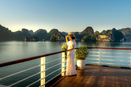 5-star Heritage Cruise on Lan Ha Bay, Quang Ninh province, Vietnam - November 13, 2020:Female tourist welcomes the sunrise on the deck of the 5-star Heritage Cruise on Lan Ha Bay, Quang Ninh, VNのeditorial素材