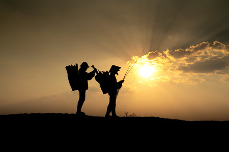 Pleiku Town, Gia Lai Province, Vietnam - March 6, 2021: Two Ede farmers collect firewood on their way home at sunset in Pleiku town, Gia Lai province, Vietnam. Silhouette.のeditorial素材