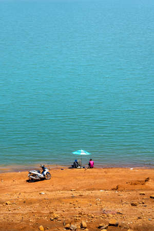 Lam Dong Province, Vietnam - March 12, 2021: A man relaxes fishing by a wild lake in Lam Dong Province, Vietnamのeditorial素材