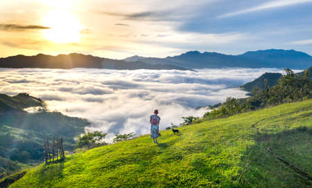 Woman on the mountain with fog in the morning at Phu Chi Fa, Chiang Rai, Thailandの写真素材