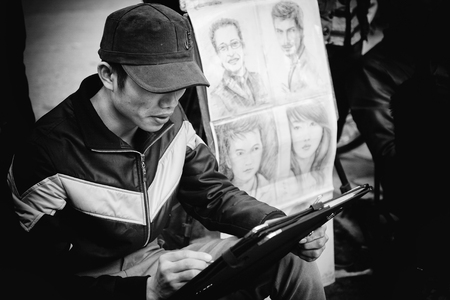Hanoi, Vietnam - January 17, 2012: The painter draw the portrait painting for customers in the sidewalkのeditorial素材
