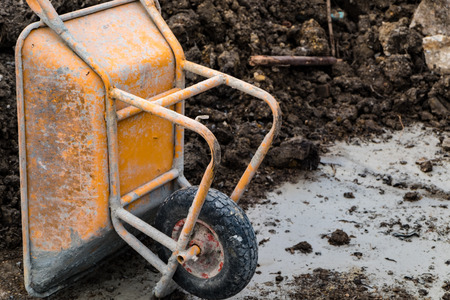 Old yellow wheelbarrow with lime stains in construction work area, selective focusの写真素材