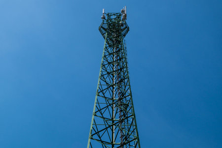 Green antenna tower with gradient blue sky background.