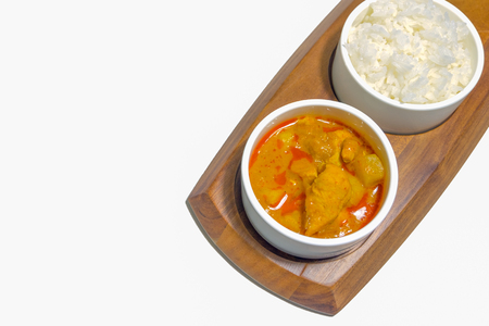 Isolate of a curry chicken with jasmin rice on nature wooden plate, on top view and white background.の写真素材