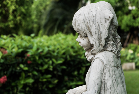A white vintage little girl ceramic scupture in the garden, selective focus.の写真素材