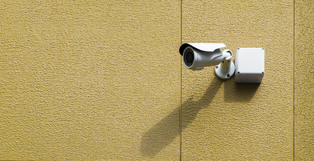 Infrared cctv camera on the exterior textured wall in yellow color with light and shadow, selective focus.の写真素材