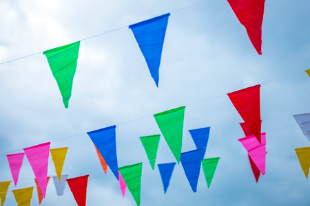 Colorful small flags paper made hanging on the rope with blue sky background, selective focus.の写真素材