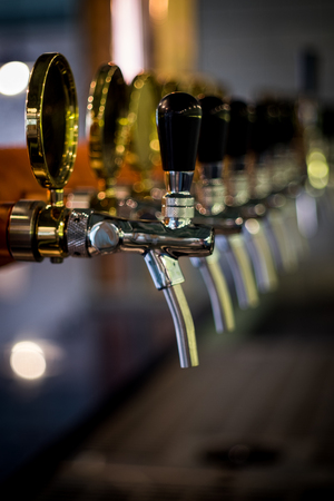 Row of draft beer tab on the top of counter bar in closeup view, time of celebration, selective focus.の写真素材