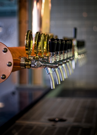 Row of draft beer tab on the top of counter bar in closeup view, time of celebration, selective focus.の写真素材