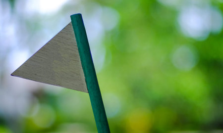 A wooden decorative white triangle flag stick with natural green environment background, selective...