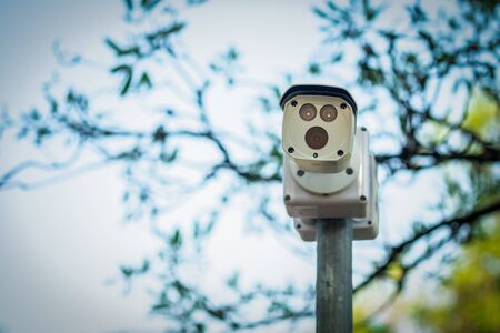 cctv security camera installed a top of round metal pole for surveillance nearby with natural background.の写真素材