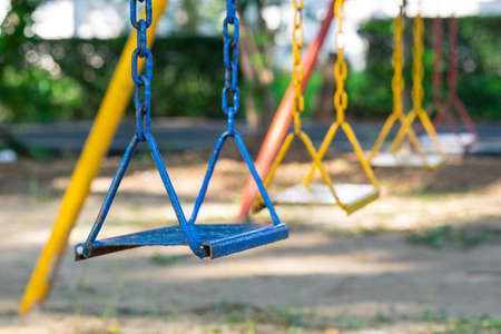 Row of multi-colored chain swing in kid playground on front focus.の写真素材