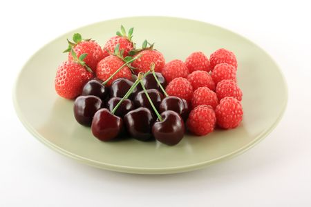 Cherry, raspberry and strawberry on a light green plateの写真素材