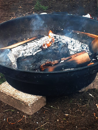 Burning firewood in a firepit on a campfire. As soon as the ashes heat up then food will be cooked...