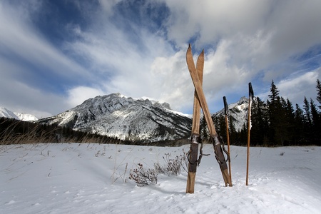 vintage skis in snow with mountains and clouds in the backgroundの写真素材