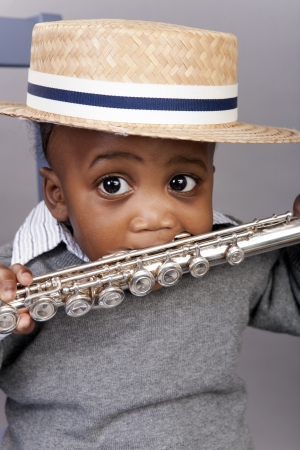 toddler holding silver flute in mouth wearing straw hatの写真素材
