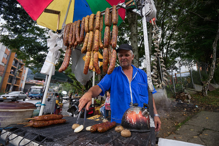 October 28, 2016 Medellin, Colombia: man frying sausages and potatoes at a roadside food stand, a popular economical fast food solution in Colombiaのeditorial素材