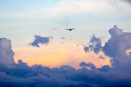 small airplane above sunset cloudsの写真素材
